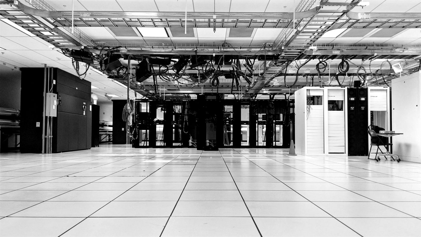 An empty data centre with rows of server cabinets and cables overhead
